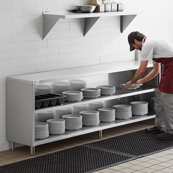 A man putting plates on a shelf in a stainless steel Regency dish cabinet.