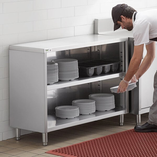 A man in a white shirt placing plates in a Regency stainless steel dish cabinet.