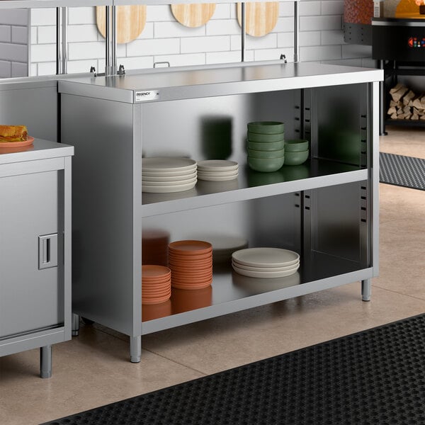 A stainless steel dish cabinet with an adjustable midshelf, shown holding various plates and bowls.