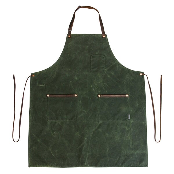 A Hardmill olive waxed canvas apron with brown straps on a table.