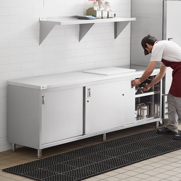 A man in a white shirt opening a Regency stainless steel cabinet.