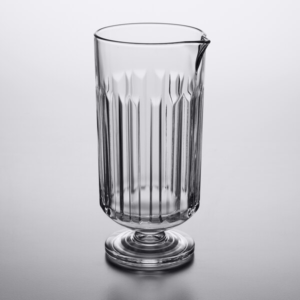 A clear glass Libbey stirring glass with a handle on a table.