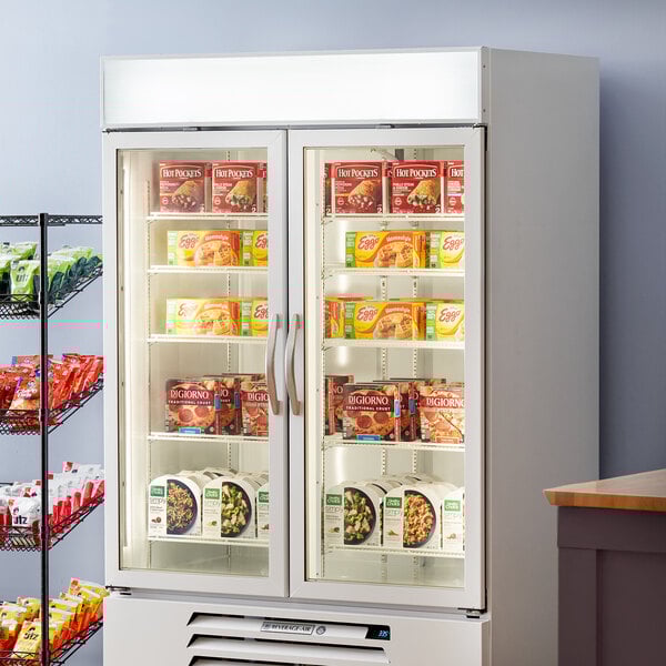 A Beverage-Air white glass door merchandiser freezer with shelves full of food.