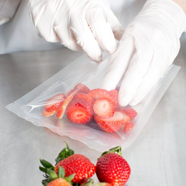 A person wearing gloves putting strawberries in a VacPak-It chamber vacuum packaging bag.