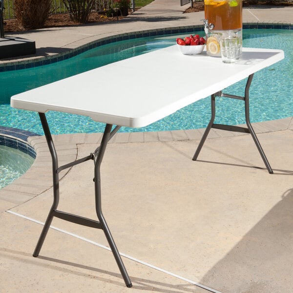 A white Lifetime fold-in-half table with bowls of fruit and liquid on it.