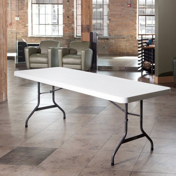 A white Lifetime plastic folding table on a tile floor.