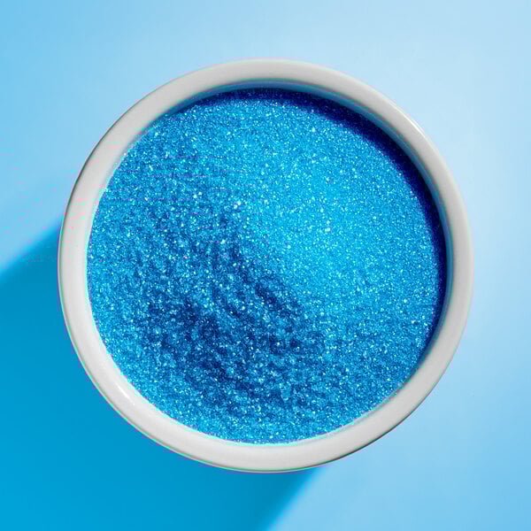 A white bowl filled with fine light blue sanding sugar.