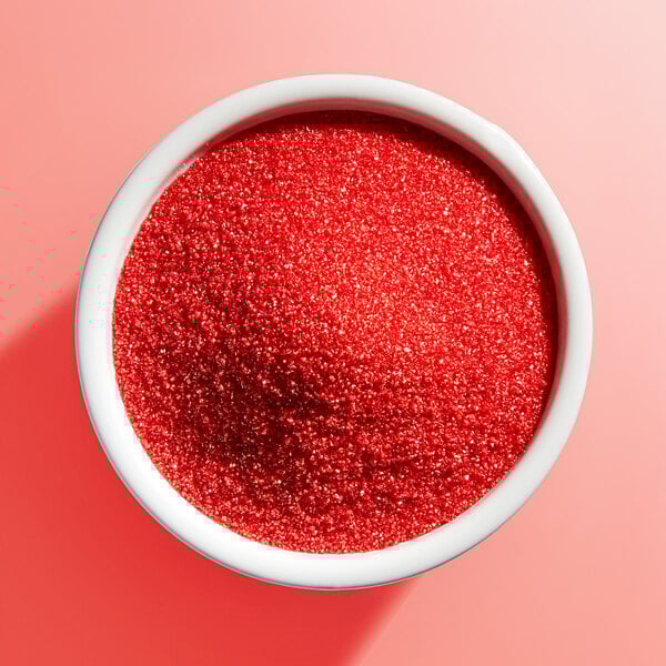 A white bowl filled with fine red sanding sugar.
