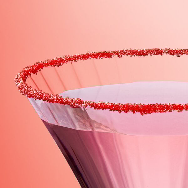 A close-up of a glass rimmed with fine red sanding sugar.