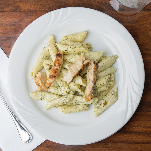 A close up of a Tuxton Sonoma bright white china plate with pasta, chicken, and cheese.