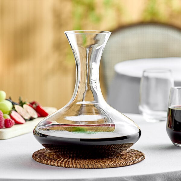 A Stolzle wine decanter filled with red wine on a table.