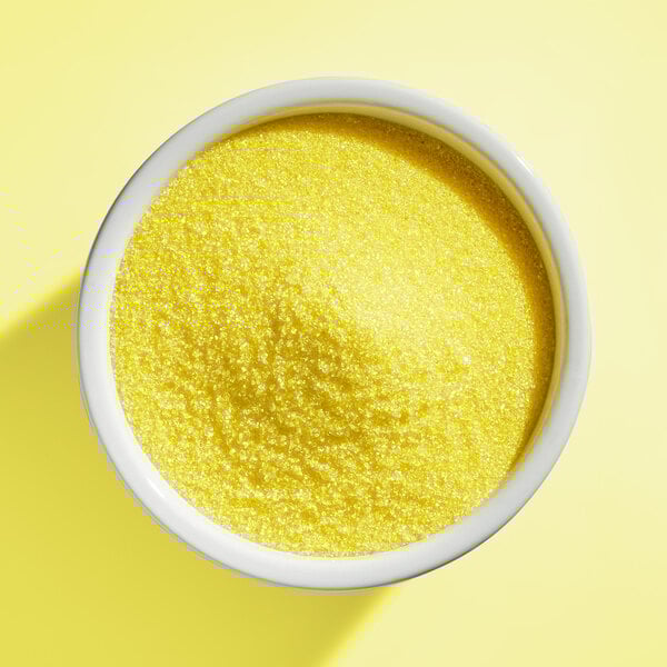 A white bowl filled with fine yellow sanding sugar.