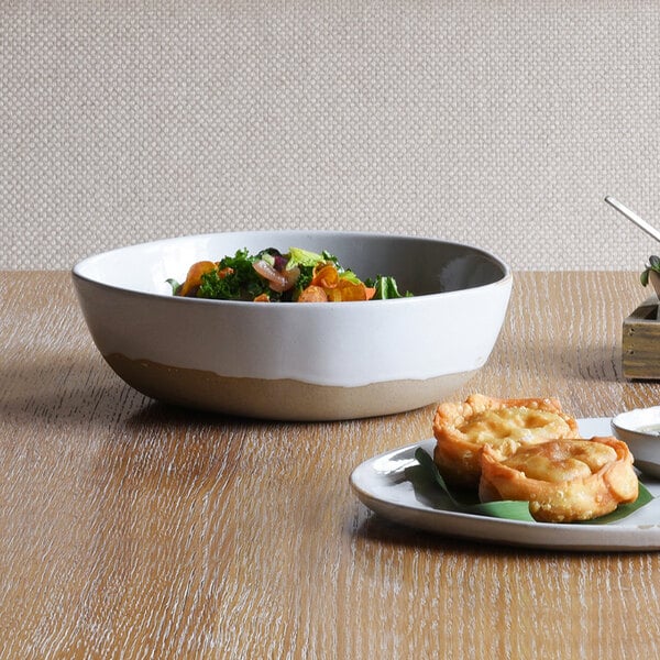 A Front of the House Artefact porcelain bowl filled with food on a table.