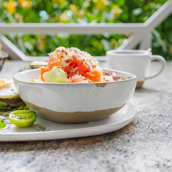 A Front of the House Artefact superwhite porcelain bowl filled with fruit on a table.