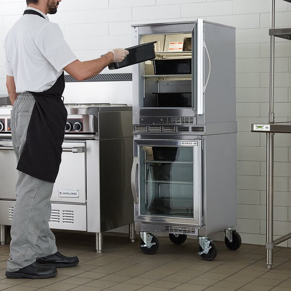 A man in a black apron standing in front of a Beverage-Air undercounter refrigerator.