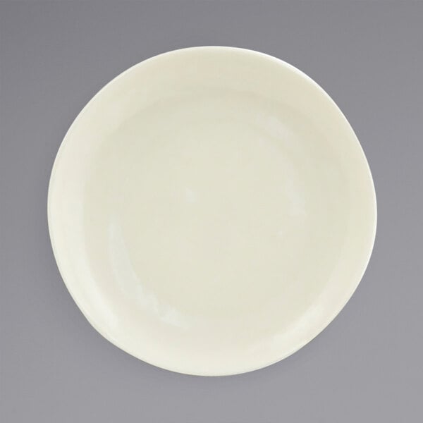 A Front of the House vanilla bean porcelain plate with a small rim on a gray surface.