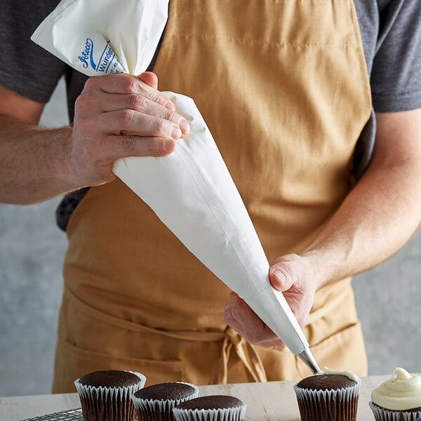 Baker using a polyurethane-lined cotton pastry bag to decorate cupcakes