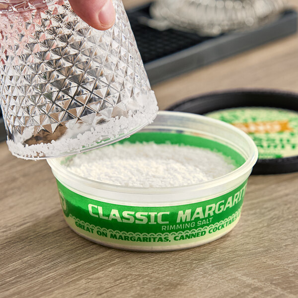 A hand pouring Twang Rimming Salt into a container.