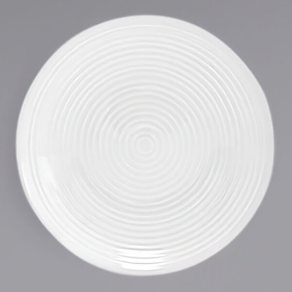 A white round porcelain sauce dish with a spiral design on the surface.