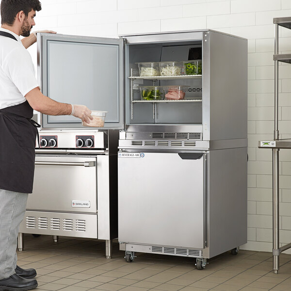 A man standing in a professional kitchen with a Beverage-Air undercounter refrigerator.