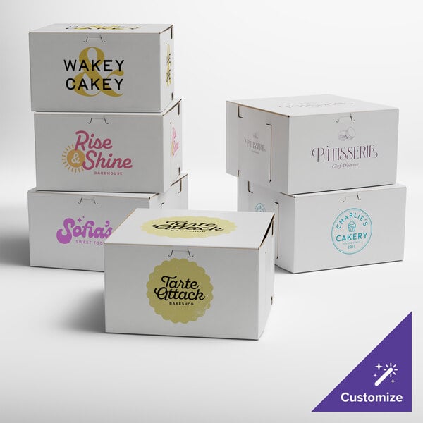 A group of white customizable cake boxes with different designs including blue, purple, pink, and yellow logos.