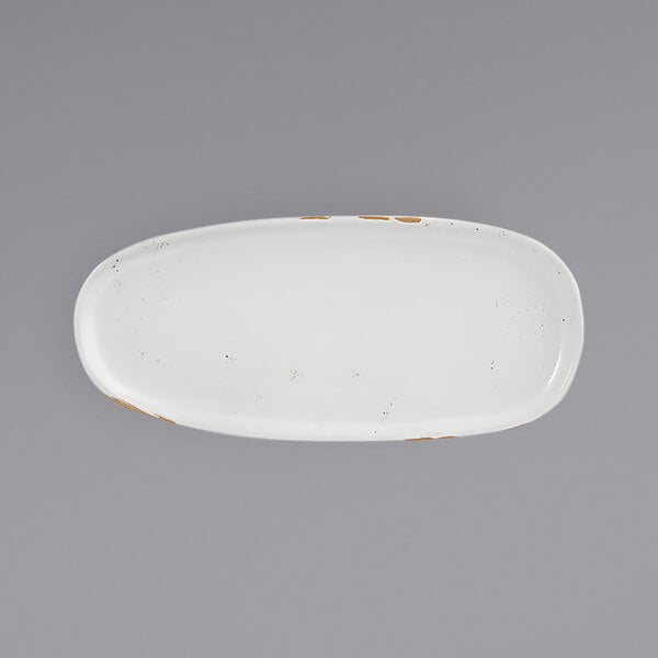 A white oval plate with brown specks.