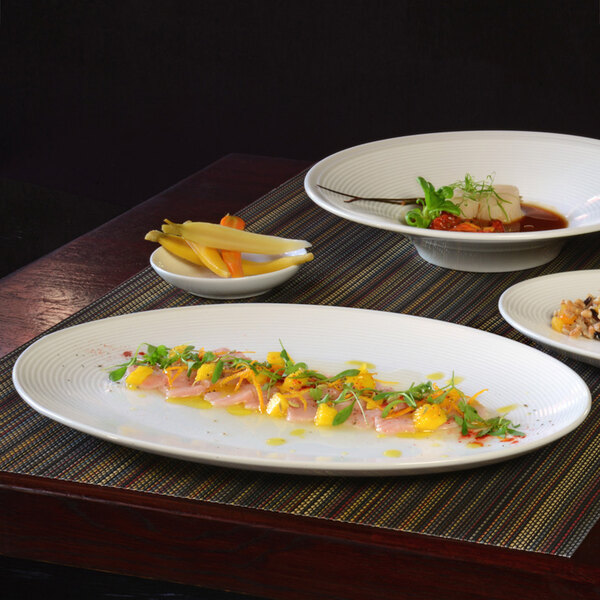 A table with Front of the House oval porcelain plates of food on it.