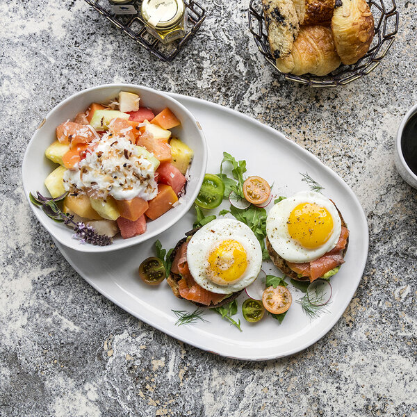 A Front of the House Artefact porcelain plate with eggs and fruit on a table.