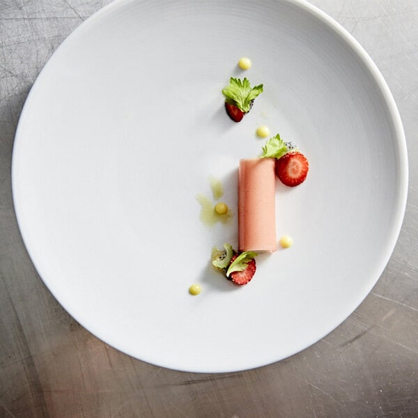 A white Front of the House porcelain plate with food on it on a table.