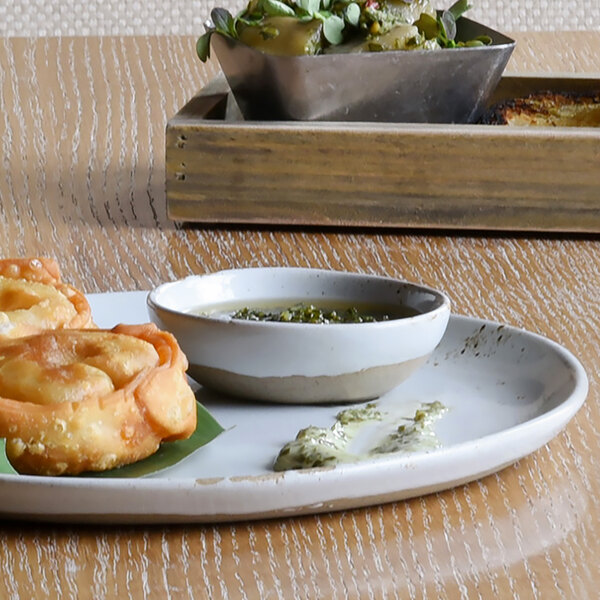 A table with a plate holding two Front of the House Artefact round ash ramekins filled with food.