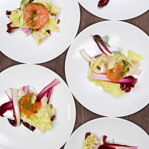 A group of Front of the House white porcelain plates with different types of food on them.