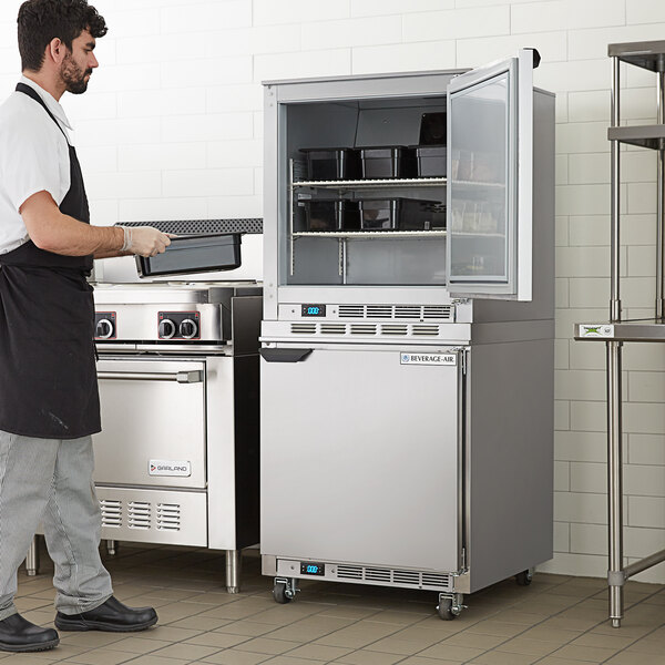 A man in a black apron standing in front of a Beverage-Air undercounter freezer.