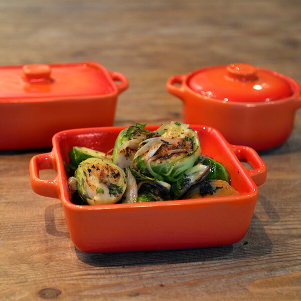 A close-up of food in a red Front of the House Kiln stoneware dish.