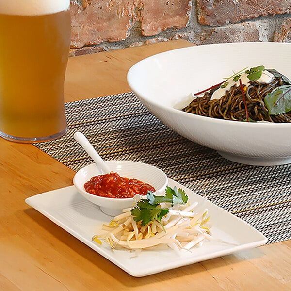 A Front of the House white rectangular porcelain plate with food and a glass of beer on a table.