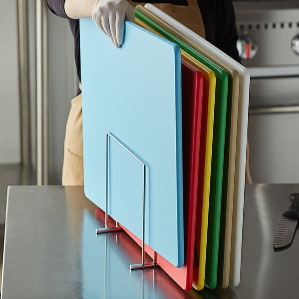 A person holding a stack of stainless steel cutting boards.