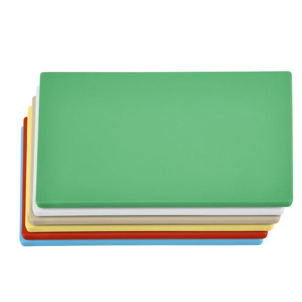 A stack of four colorful plastic cutting boards in green, white, yellow, and red.