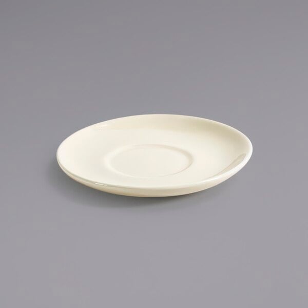 A white porcelain saucer with a small rim on a gray surface.