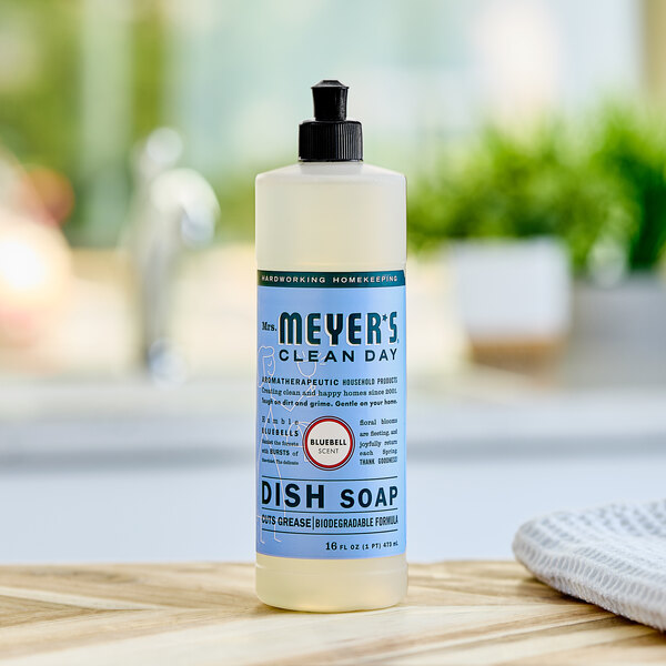 A bottle of Mrs. Meyer's Bluebell scented dish soap on a wooden table.