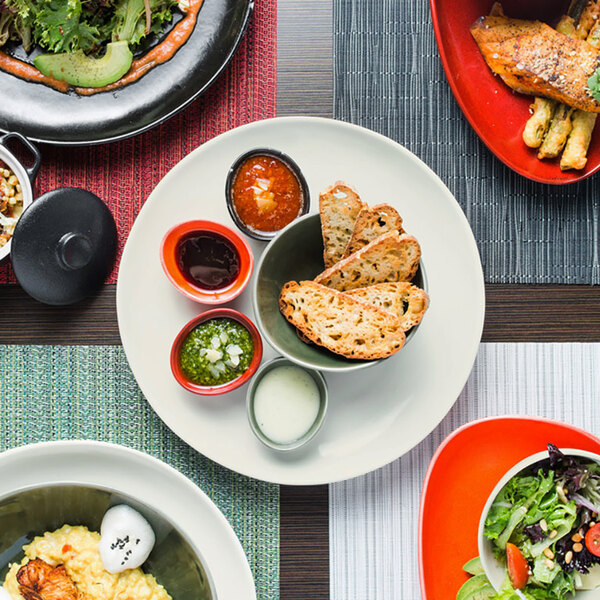 An orange table with a variety of food on white porcelain plates.