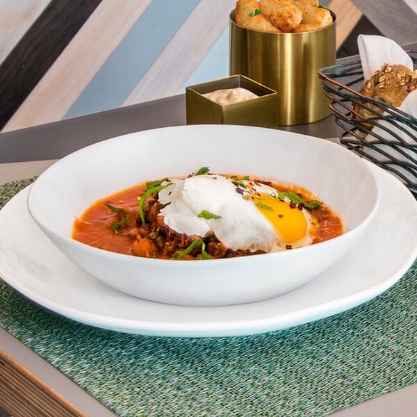 A white Front of the House porcelain bowl of soup with an egg on top.