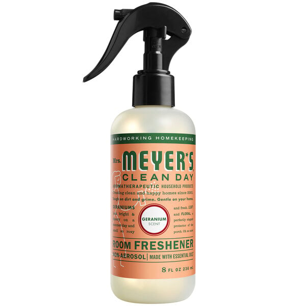 A close-up of a Mrs. Meyer's Clean Day Geranium Air Freshener spray bottle with a black handle.