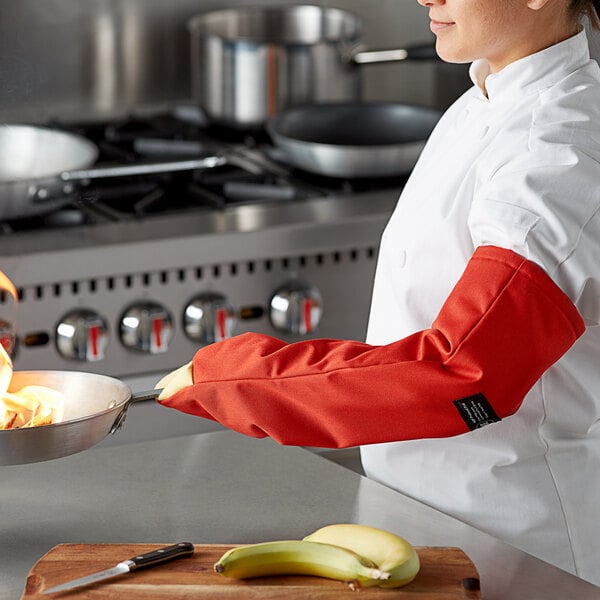 A chef using a San Jamar Cool Touch oven mitt to cook over a stove.