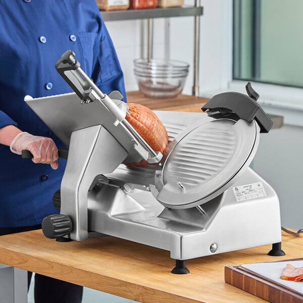 A person in a blue uniform and gloves using a Centerline by Hobart meat slicer to slice meat.