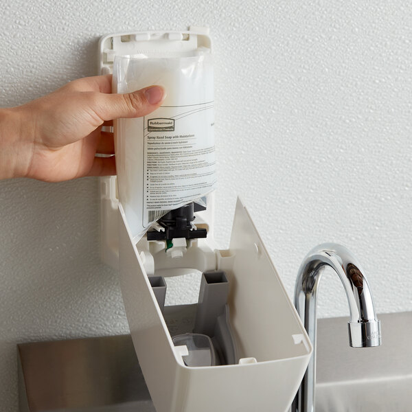 A hand using a white Rubbermaid manual surface cleaner dispenser.