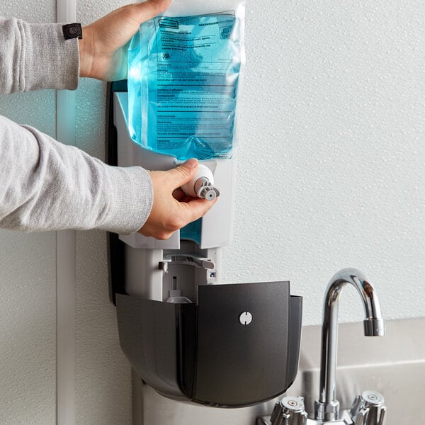 A person using a black Rubbermaid Autofoam soap dispenser.