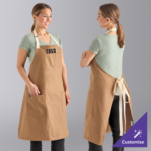 A woman wearing a brown Uncommon Chef Rebel bib apron with natural webbing.