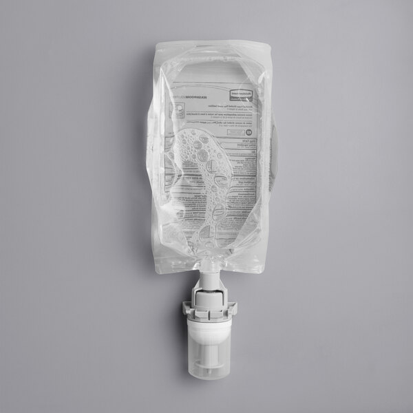 A bottle of Rubbermaid Flex Enriched Foam Alcohol Hand Sanitizer with a white cap on a gray surface.