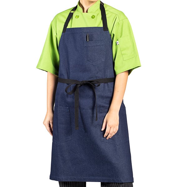 A woman wearing an indigo denim Uncommon Chef bib apron with black webbing.