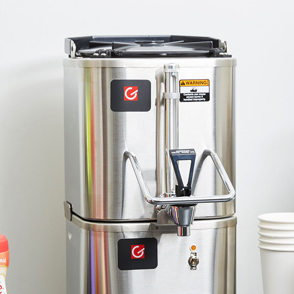 A Grindmaster stainless steel coffee shuttle with a faucet.