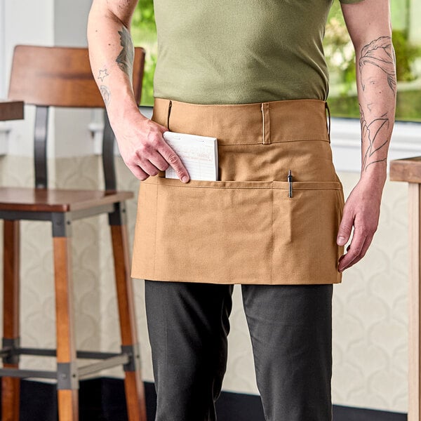 A man wearing a brown Uncommon Chef waist apron with natural webbing.